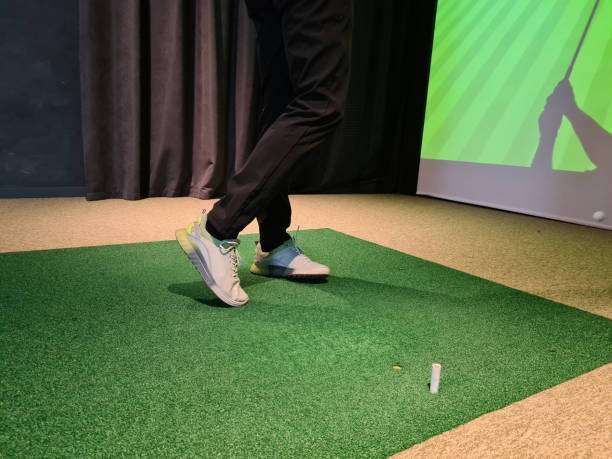 Legs of man playing golf on screen. Young golfer playing golf video game indoors on simulator